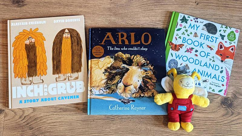 The Bookbug Picture Book Prize 2022 shortlisted books (Inch And Grub, Arlo the lion who couldn't sleep, and My First Book Of Woodland Animals) displayed next to Bookbug doll